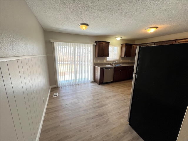 kitchen with light wood finished floors, stainless steel appliances, light countertops, visible vents, and dark brown cabinets