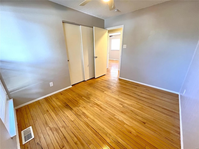 unfurnished bedroom featuring baseboards, a closet, visible vents, and light wood-style floors