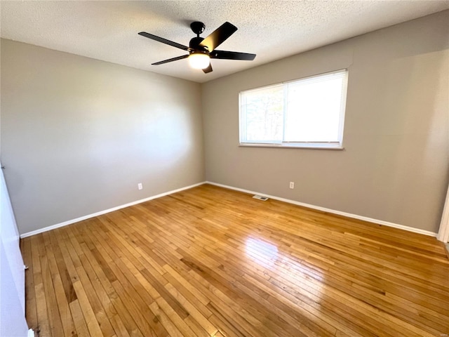 empty room featuring a ceiling fan, light wood-type flooring, a textured ceiling, and baseboards