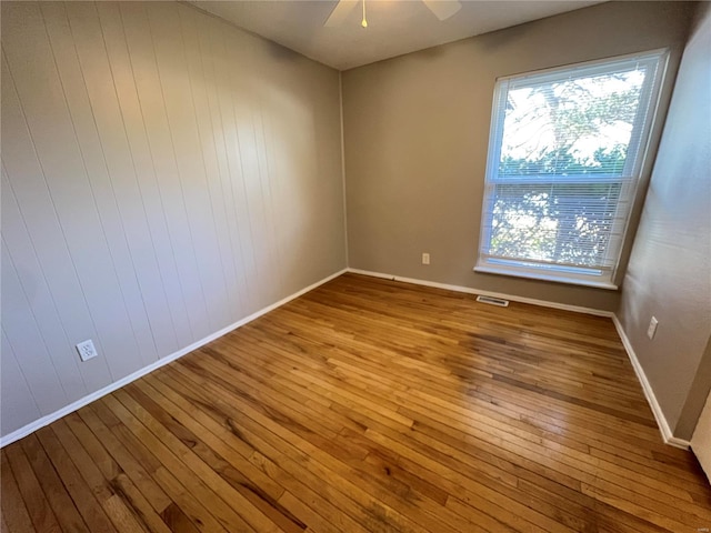 unfurnished room featuring ceiling fan, hardwood / wood-style flooring, visible vents, and baseboards