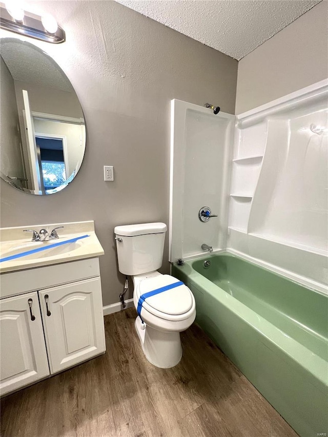 bathroom with shower / bath combination, toilet, a textured ceiling, vanity, and wood finished floors