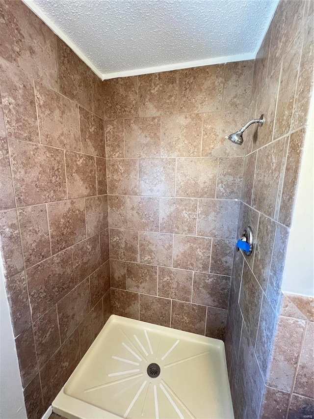 bathroom with a tile shower and a textured ceiling