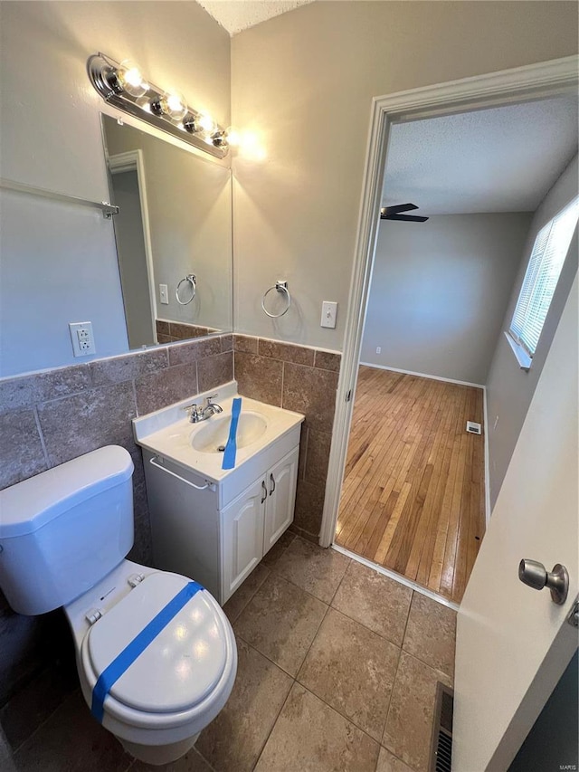 bathroom with wainscoting, toilet, tile patterned floors, vanity, and tile walls