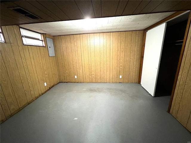 basement with electric panel and wooden walls