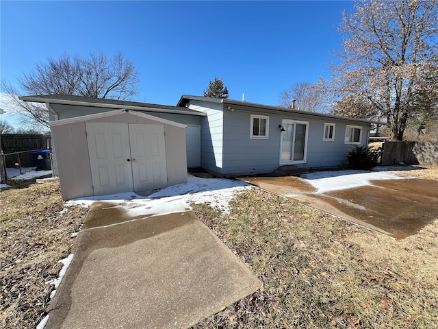 exterior space featuring an outbuilding, a patio, a storage unit, and fence