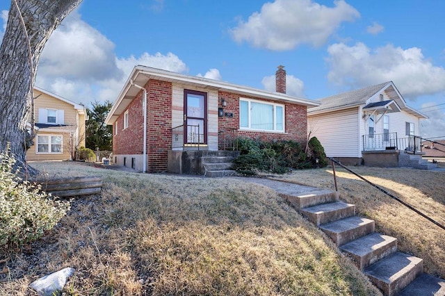 view of front of home with brick siding and a chimney