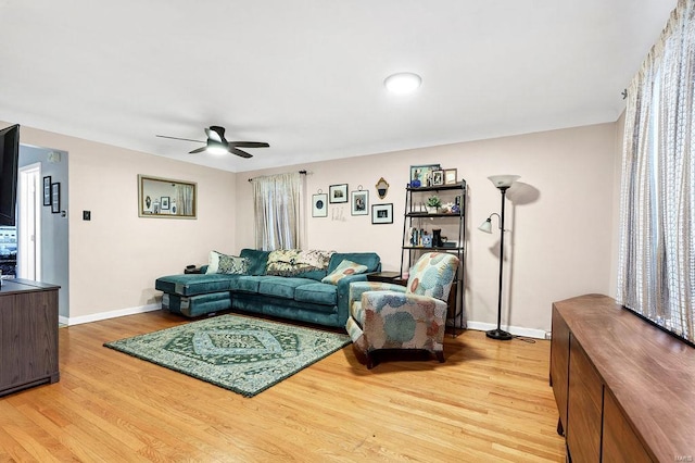 living room with a ceiling fan, baseboards, and light wood finished floors