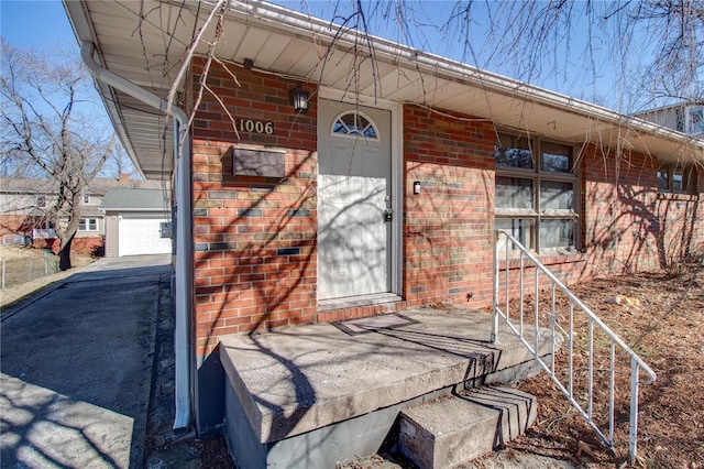 view of exterior entry featuring a porch and brick siding