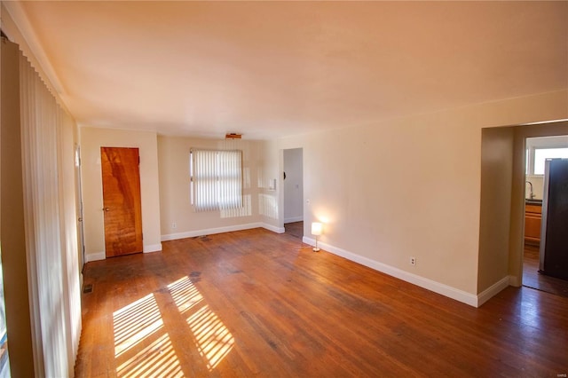 unfurnished room featuring a wealth of natural light, baseboards, and wood finished floors