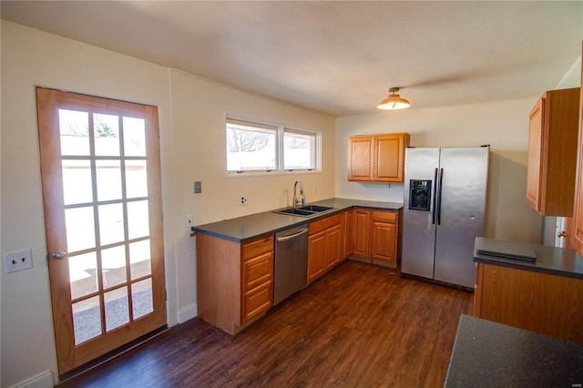 kitchen with stainless steel appliances, dark countertops, dark wood-type flooring, and a sink