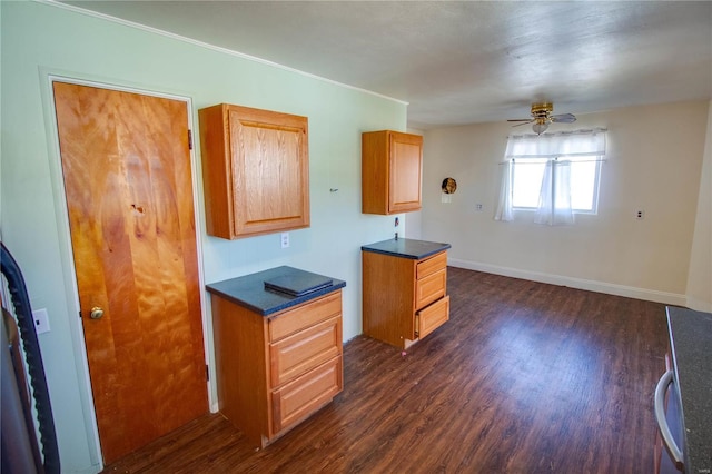 kitchen featuring dark countertops, baseboards, a ceiling fan, and dark wood-style flooring