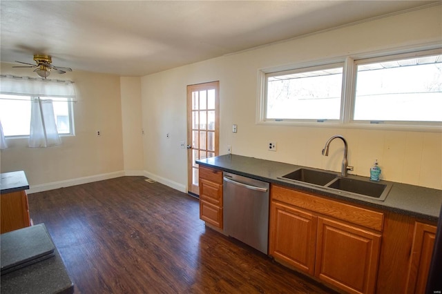 kitchen with dark wood-style flooring, a sink, brown cabinets, dishwasher, and dark countertops