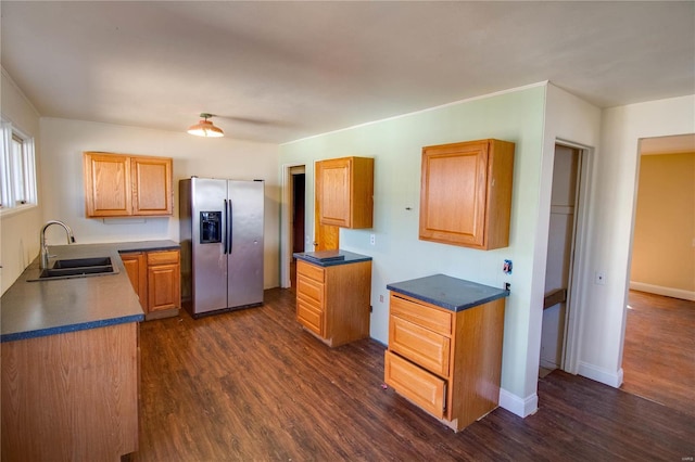 kitchen with dark wood-style flooring, a sink, stainless steel refrigerator with ice dispenser, and baseboards