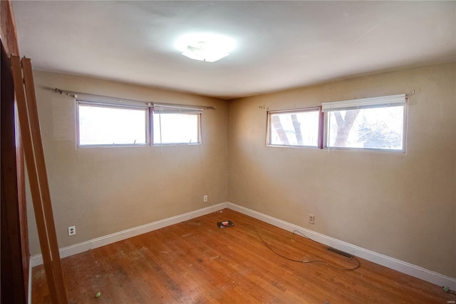 spare room featuring visible vents, baseboards, and wood finished floors