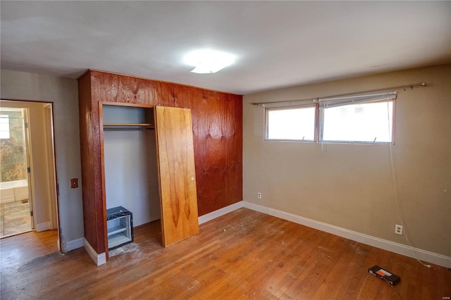 unfurnished bedroom featuring a closet, baseboards, and wood finished floors