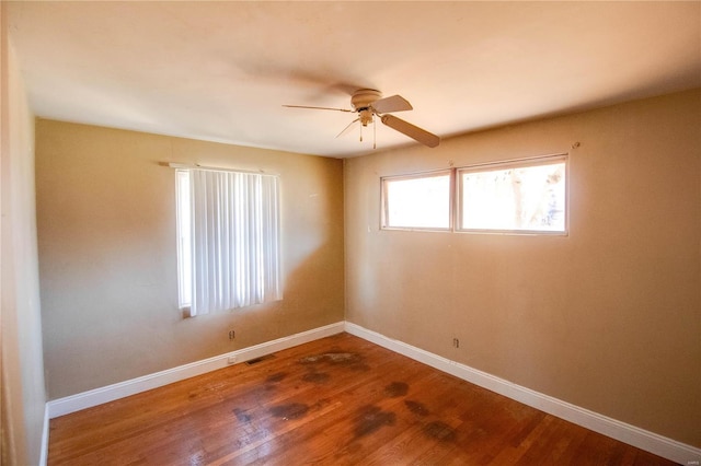 spare room featuring ceiling fan, visible vents, baseboards, and wood finished floors