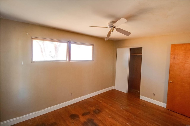 unfurnished bedroom featuring a closet, wood finished floors, a ceiling fan, and baseboards