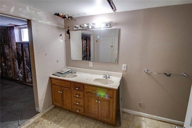 full bath featuring a sink, baseboards, and double vanity