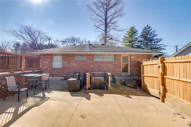 rear view of house featuring a patio, brick siding, fence, and a gate