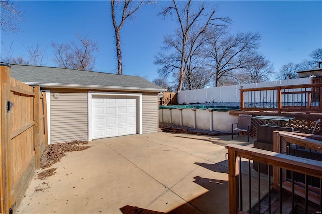 garage featuring a covered pool, fence, and concrete driveway