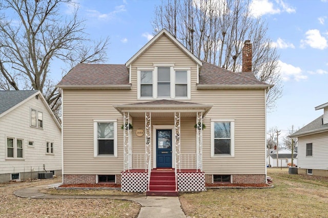 view of front of property with a shingled roof, central AC unit, a chimney, covered porch, and a front yard