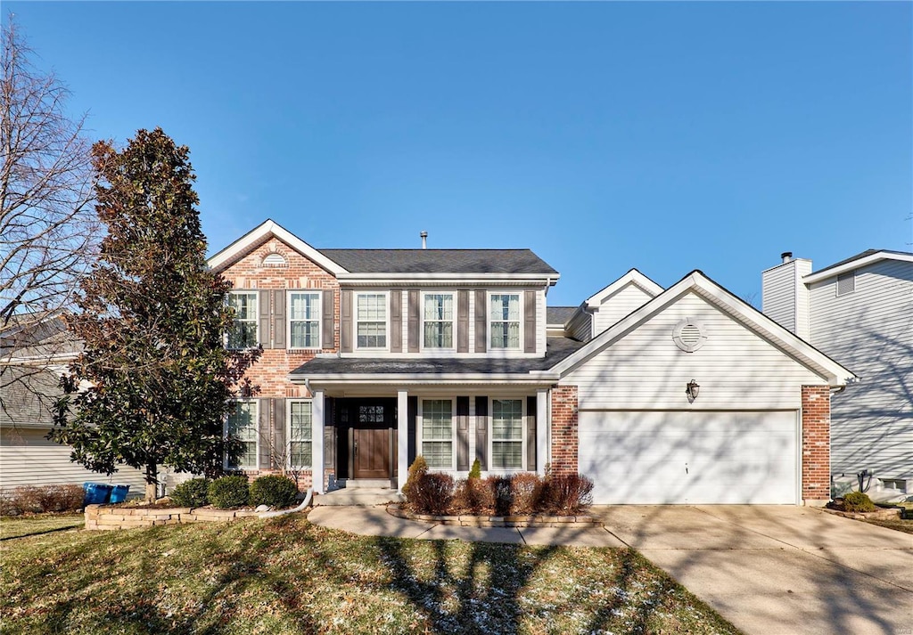 colonial home featuring a garage, driveway, and brick siding