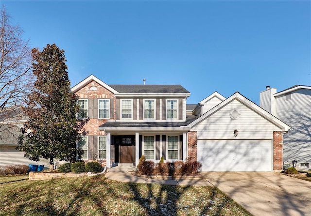 colonial home featuring a garage, driveway, and brick siding