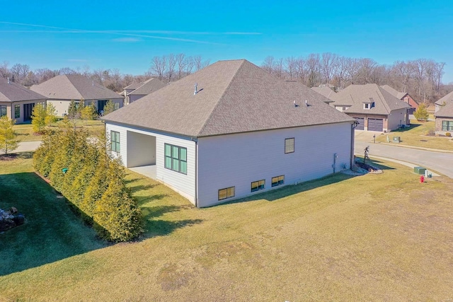 exterior space with a residential view, roof with shingles, and a lawn