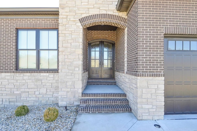 view of exterior entry with stone siding, french doors, and brick siding