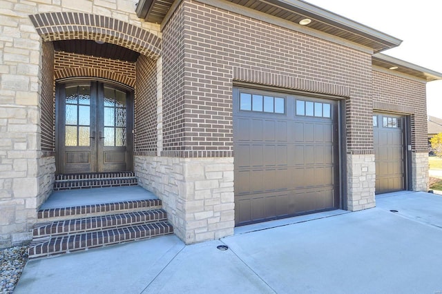 property entrance featuring stone siding, french doors, brick siding, and driveway