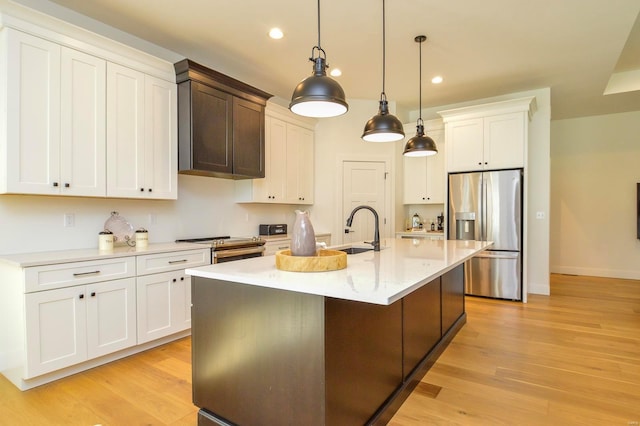 kitchen featuring light wood-style flooring, a center island with sink, stainless steel appliances, and a sink