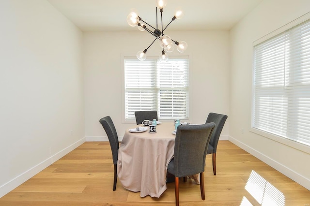 dining area featuring a chandelier, baseboards, and light wood finished floors