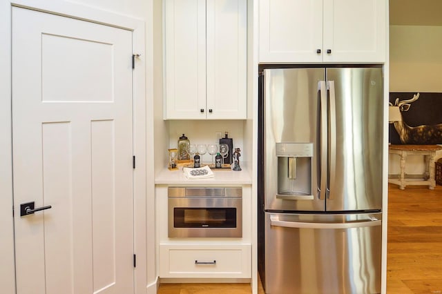 kitchen featuring appliances with stainless steel finishes, light wood-type flooring, light countertops, and white cabinets