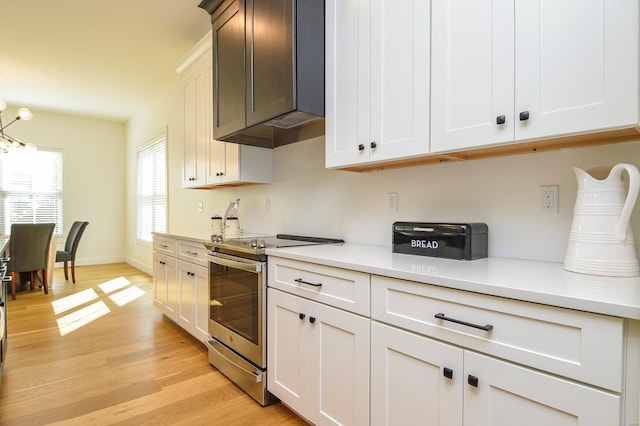 kitchen featuring light countertops, light wood-style floors, white cabinets, and stainless steel range with electric cooktop