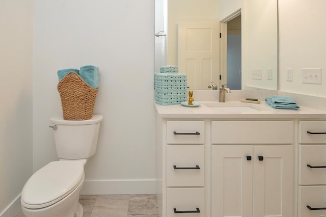 bathroom featuring toilet, baseboards, and vanity