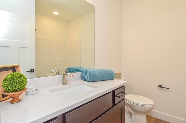 bathroom featuring recessed lighting, toilet, vanity, wood finished floors, and baseboards