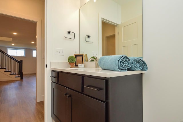 bathroom with recessed lighting, baseboards, wood finished floors, and vanity