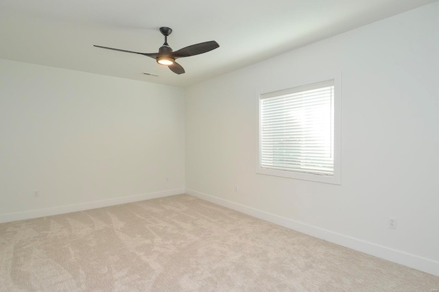 spare room featuring baseboards, visible vents, a ceiling fan, and light colored carpet