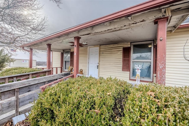 view of exterior entry with ceiling fan and a porch