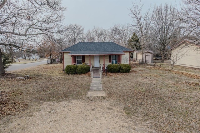 bungalow-style home featuring a porch, a shingled roof, and fence