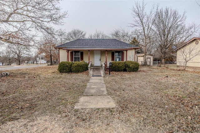 bungalow with a shingled roof, fence, and a porch