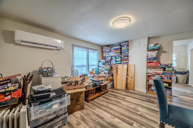 home office with light wood-type flooring, an AC wall unit, and a textured ceiling