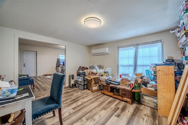 home office featuring a wall unit AC, a textured ceiling, and wood finished floors