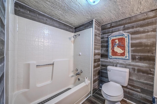 bathroom with tub / shower combination, wood finished floors, and toilet