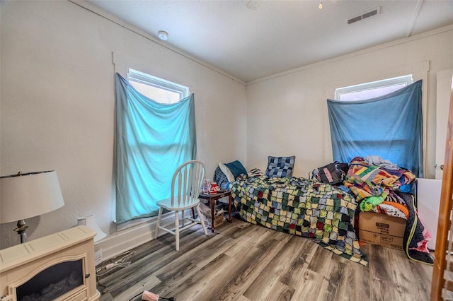 bedroom featuring crown molding, visible vents, and wood finished floors