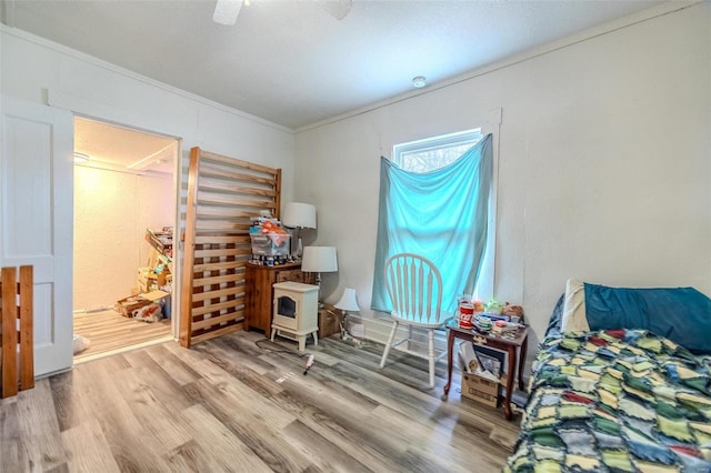 bedroom featuring ceiling fan, wood finished floors, and crown molding