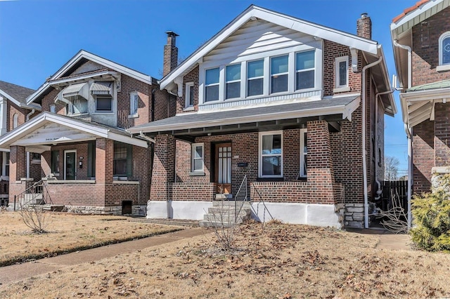 view of front of house featuring brick siding, covered porch, and a chimney