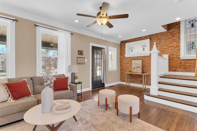 living area featuring stairway, brick wall, and a wealth of natural light