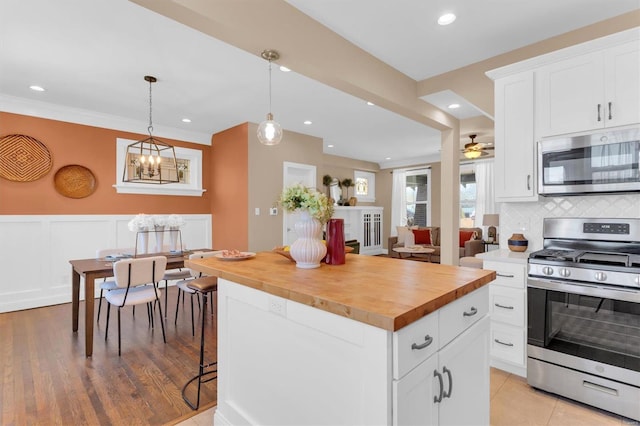 kitchen featuring tasteful backsplash, butcher block countertops, appliances with stainless steel finishes, and a center island