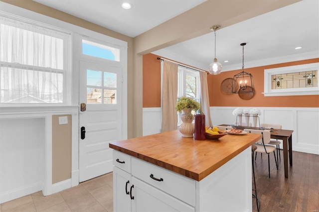 kitchen featuring white cabinets, decorative light fixtures, a wainscoted wall, and wood counters